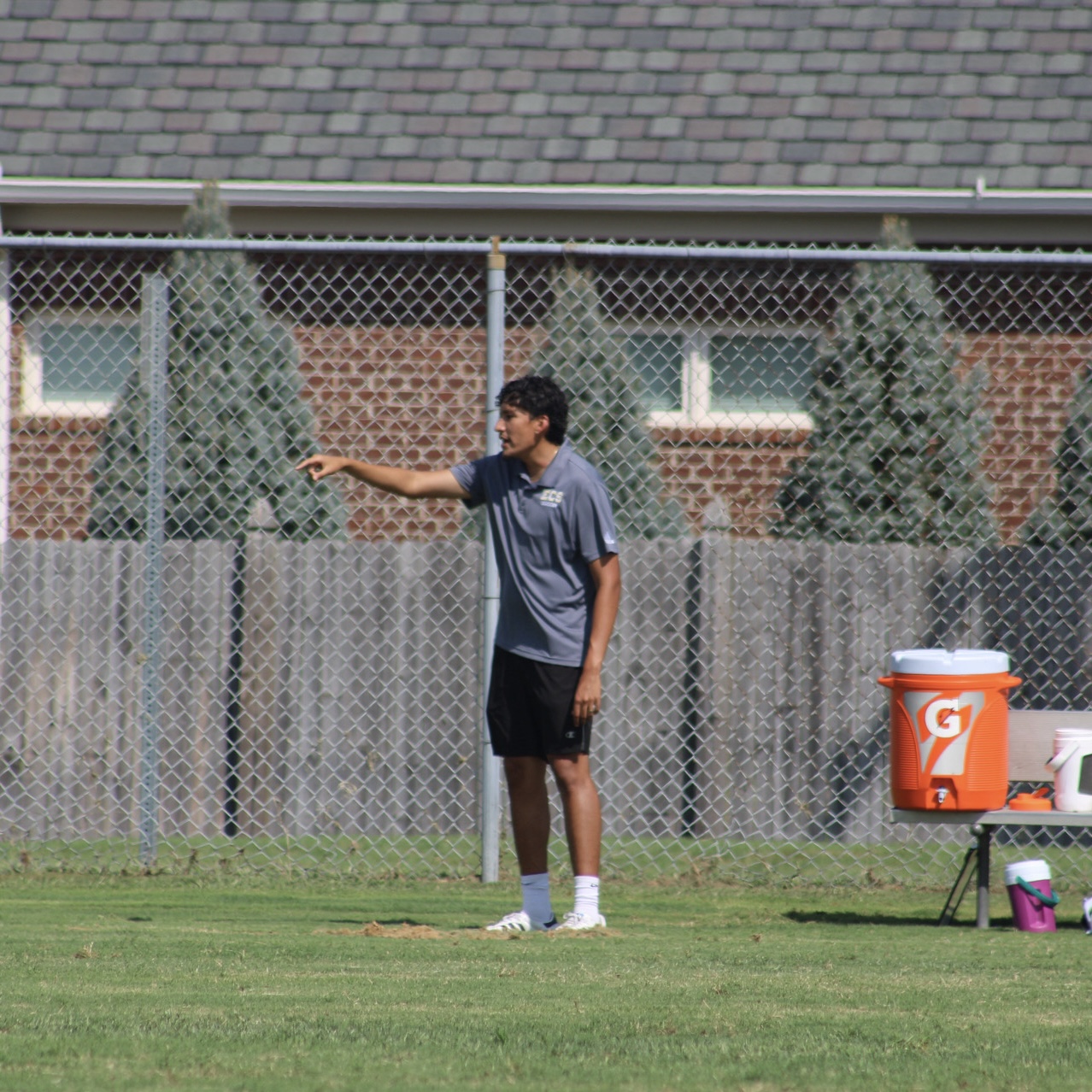 Coach Alex pointing across the soccer field while coaching from the sideline